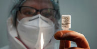 Медик набирает вакцину Спутник V в шприц для инъекции
