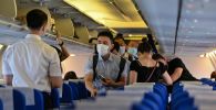 Пассажиры в защитных масках в салоне самолета, архивное фото