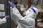 Медик в защитном костюме ловит снежинки на улице в перерыве смены в больнице с коронавирусом