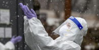 Медик в защитном костюме ловит снежинки на улице в перерыве смены в больнице с коронавирусом