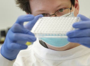 Сотрудник лаборатории изучает пробирки с положительными пробами на коронавирус