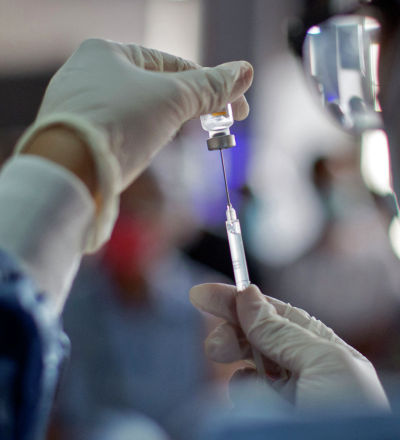 Медик набирает в шприц вакцину от коронавируса