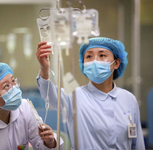 Медсестры в защитных костюмах поправляют капельницы в больнице с коронавирусом