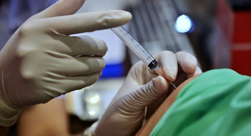 Медик делает пациенту прививку от коронавируса 
