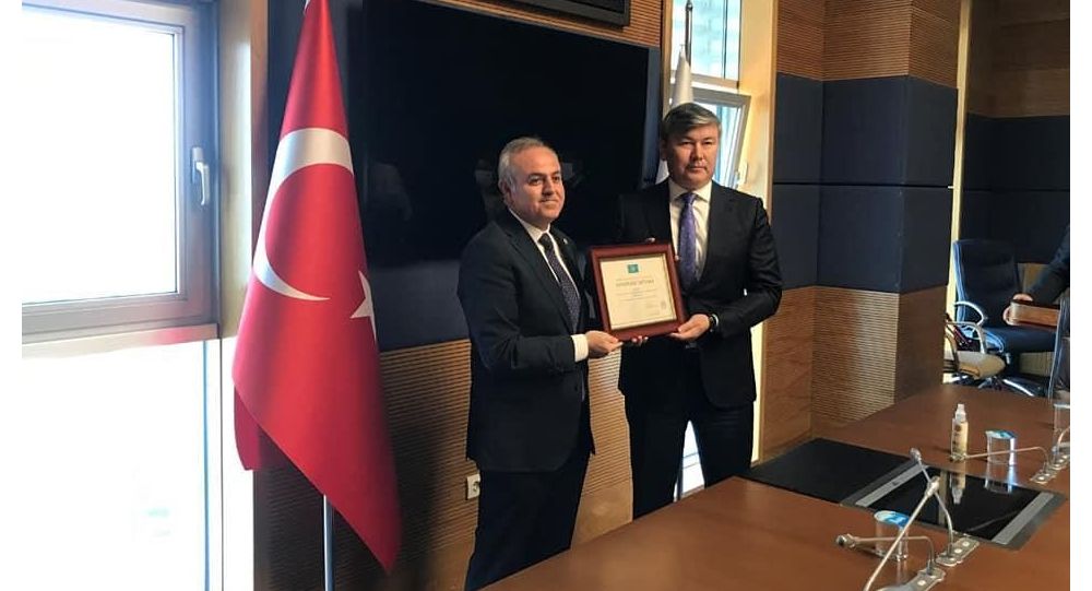 Казахстанский посол Абзал Сапарбекулы вручает благодарственную грамоту турецкому врачу Реджепу Шекеру