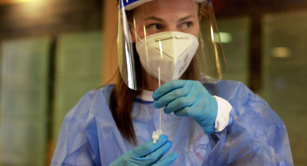 Медик в защитном костюме готовится взять пробу для ПЦР-анализа на коронавирус