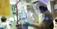 Медик в защитном костюме проверяет апааратуру в отделении реанимации в больице с коронавирусом 