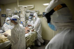 Врачи в защитных костюмах работают с пациентом в палате реанимации в больнице с коронавирусом 