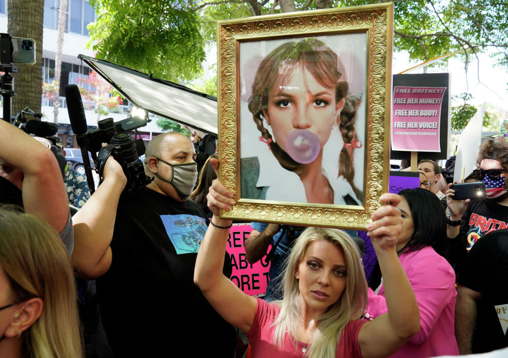 Сторонник Бритни Спирс Стефани Льюис из Лос-Анджелеса держит портрет поп-певицы перед слушанием слушаний по поводу опекунства в здании суда Стэнли Моск в среду, 14 июля 2021 года, в Лос-Анджелесе