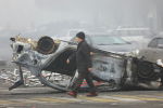Мужчина проходит мимо машины, сгоревшей во время акций протеста в Алматы.