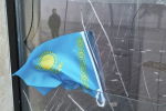 Государственный флаг Казахстана на разбитом окне отделения Kaspi Bank в Алматы