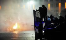Полицейская машина горит, когда ОМОН готовится остановить демонстрантов в центре Алматы, Казахстан, среда, 5 января 2022 г. 