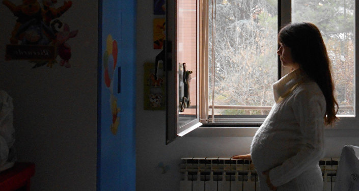 Беременная женщина у окно, архивное фото
