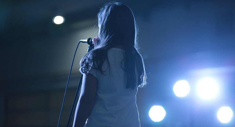 Девочка исполняет песню на сцене