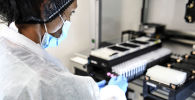 Сотрудница лаборатории проводит исследование образцов тестов на коронавирус