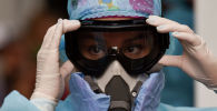 Девушка-медик поправляет защитные очки и респиратор в больнице с коронавирусом 