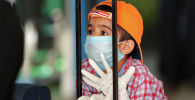 Ребенок в защитной маске и перчатках опирается на чемодан в ожидании рейса