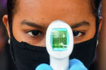 Девушка в маске ожидает, когда врач измерит ей температуру
