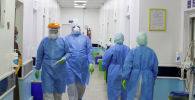 Медики в защитных костюмах в коридоре больницы с коронавирусом