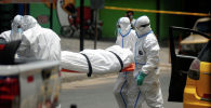 Работники больницы в защитных костюмах транспортируют тело погибшего от коронавируса