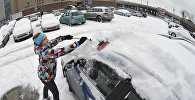 Женщина чистит машину от снега