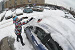 Женщина чистит машину от снега