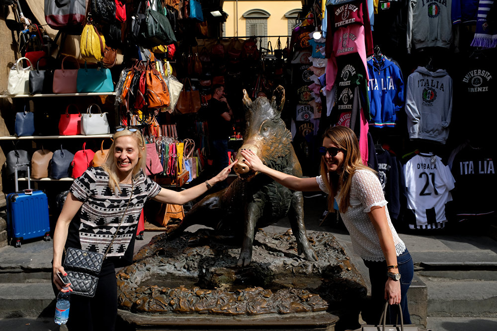 Туристы позируют у фонтана Porcellino, местного флорентийского прозвища бронзового фонтана кабана