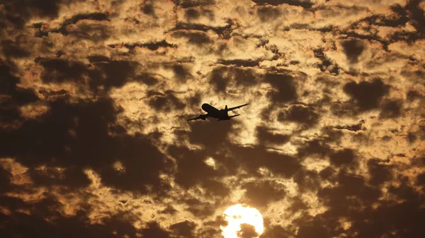 Силуэт самолета на фоне пылающих в заходящем солнце облаков в Ахмедабаде, Индия - Sputnik Казахстан
