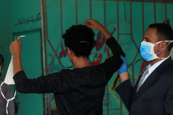 Охранник в защитной маске проверяет старшеклассника перед экзаменами в Каире, Египет - Sputnik Казахстан