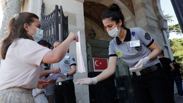 Студент в защитной маске показывает свои документы в главном кампусе Стамбульского университета в Стамбуле, Турция - Sputnik Казахстан