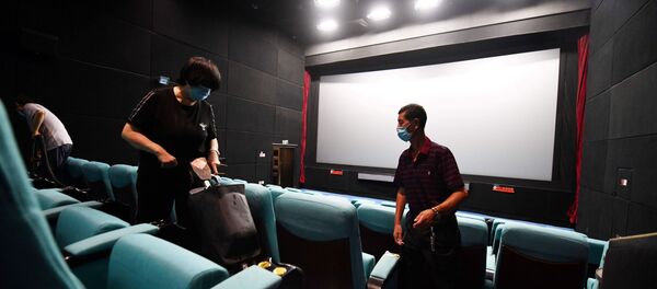 Работники кинотеатра в масках делают уборку в зрительном зале - Sputnik Казахстан