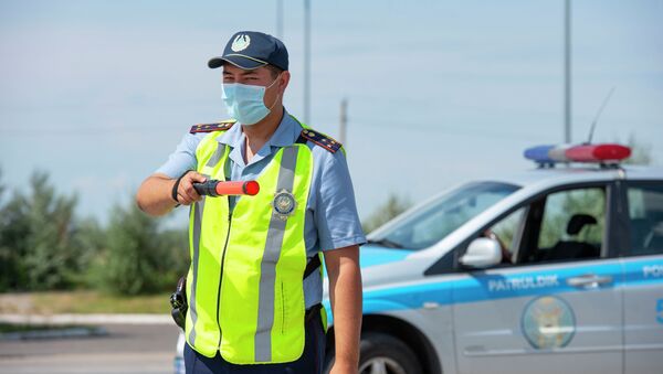 Патрульный полицейский в маске с жезлом на дороге - Sputnik Казахстан