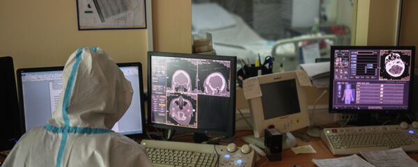 Врач в защитном костюме изучает данные томографии - Sputnik Казахстан