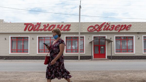 Женщина в маске проходит мимо закрытого ресторана в поселке - Sputnik Казахстан