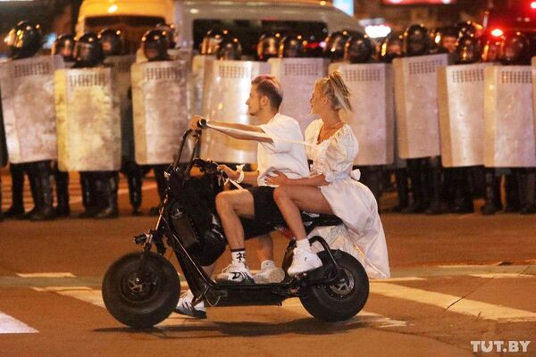 Пара на скутере напротив полицейских во время протестов в Минске  - Sputnik Казахстан