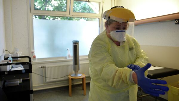 Медсестра надевает новые перчатки в больнице с коронавирусом - Sputnik Казахстан