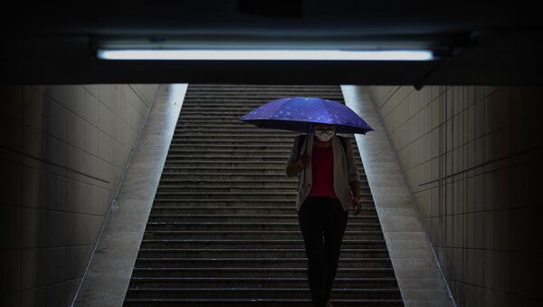 Девушка в маске под зонтом спускается в подземный переход - Sputnik Қазақстан