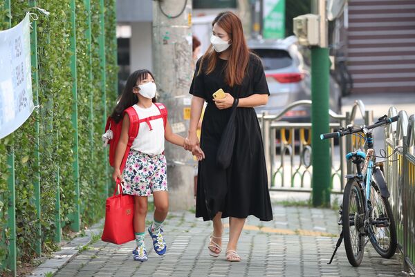 Мама с дочерью в медицинских масках по дороге в начальную школу в Сеуле, Южная Корея - Sputnik Казахстан