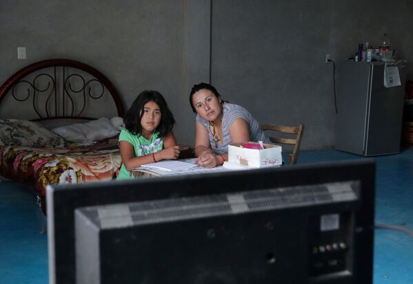 Мать и дочь смотрят урок по ТВ во время самоизоляции в Мексике - Sputnik Казахстан