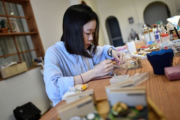 Вьетнамская художница Nguyen Thi Ha An с миниатюрной тарелкой с едой в своей студии в Ханое  - Sputnik Казахстан