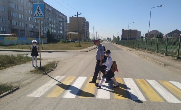 Полицейский переводит школьников через дорогу по пешеходному переходу  - Sputnik Қазақстан