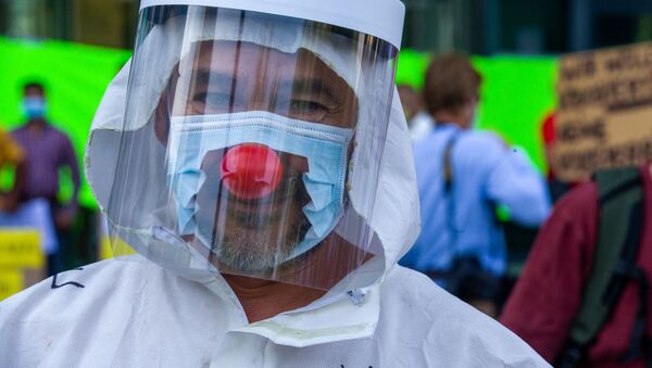Мужчина в маске и с клоунским носом во время протестов в Брюсселе - Sputnik Казахстан