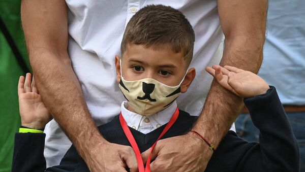 Ребенок в защитной маске рядом со взрослым возле школы  - Sputnik Казахстан
