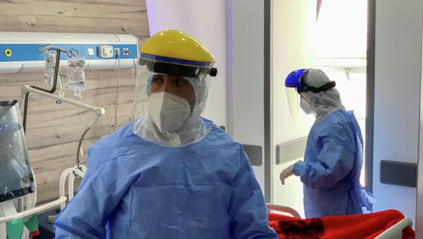 Врач в защитном костюме выходит из палаты интенсивной терапии в больнице с коронавирусом - Sputnik Казахстан