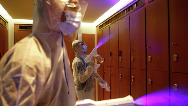 Работники в защитных костюмах проводят дезинфекцию в помещении - Sputnik Қазақстан