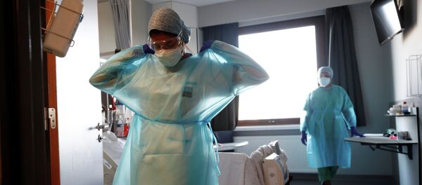 Медик поправляет защитный костюм, выходя из палаты в больнице с коронавирусом Медик поправляет защитный костюм, выходя из палаты в больнице с коронавирусом - Sputnik Казахстан
