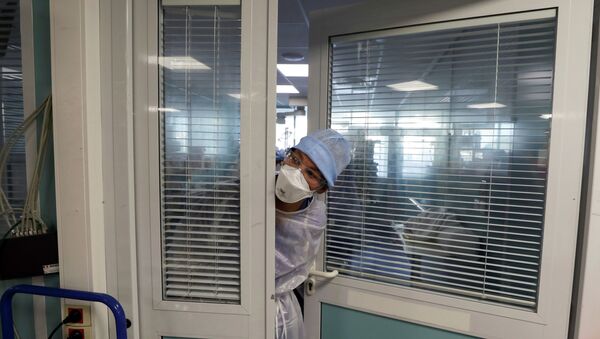 Медсестра в защитном костюме заглядывает в палату в больнице с коронавирусом - Sputnik Казахстан