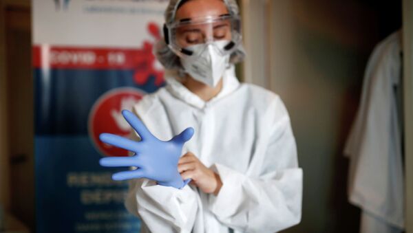 Врач в защитном костюме надевает перчатки в больнице с коронавирусом  - Sputnik Казахстан