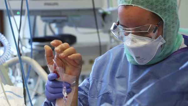 Врач держит руку пациента в палате интенсивной терапии в больнице с коронавирусом  - Sputnik Казахстан