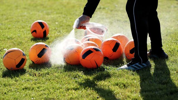 Тренер обрабатывает антисептиком  мячи на футбольном поле перед началом тренировки  - Sputnik Казахстан